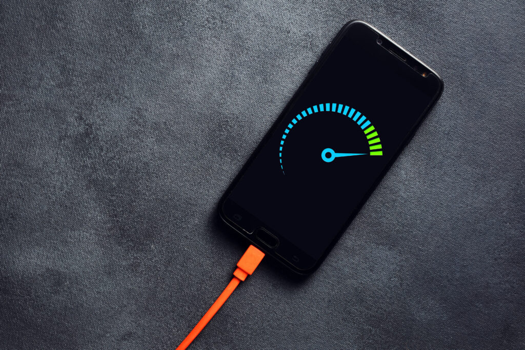 Smartphone connected to a usb charging cable and fast charging on black background. Phone fast and quick speed charge.